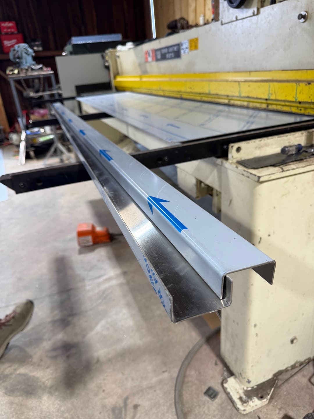 Metal sheet bending machine with aluminum profile ready for shaping in a workshop.