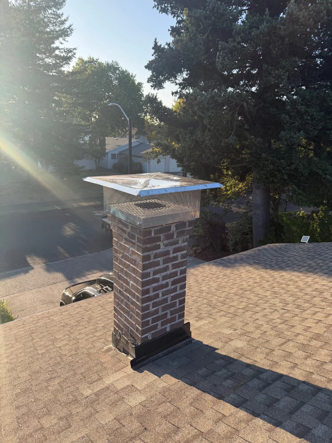 Chimney on a rooftop with sunlight, showcasing a brick structure and clear sky.