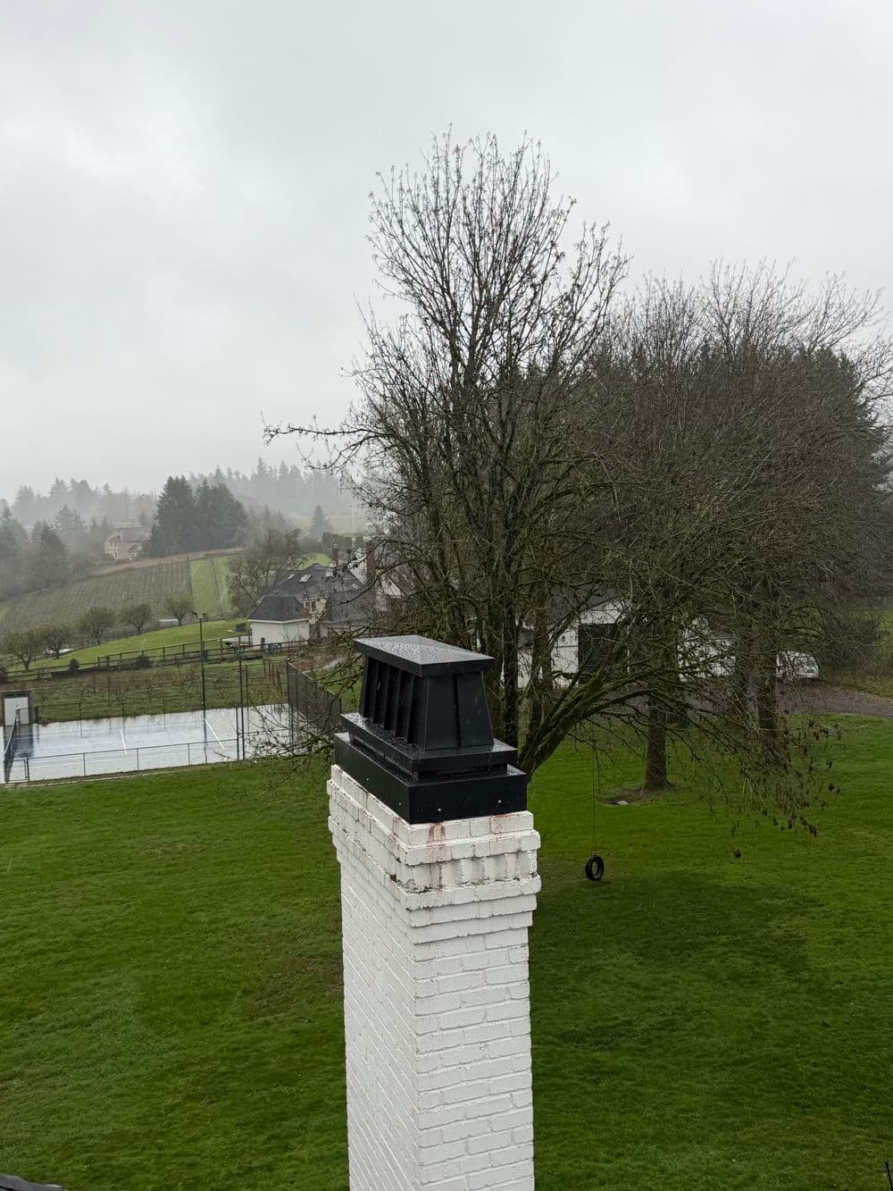 Chimney atop a white brick structure with a misty, green landscape in the background.