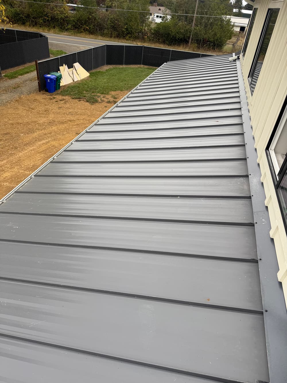 Metal roof installation on a residential building with a sloped design and clear surroundings.